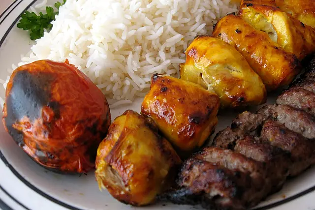 Koobideh and saffron chicken kabobs with rice and a charred tomato